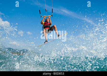 Un excellent kite surfer obtient un peu d'air qu'il vole jusqu'au large d'une vague Banque D'Images