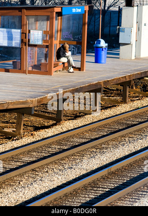 Une jeune femme attend son train sortant. Banque D'Images