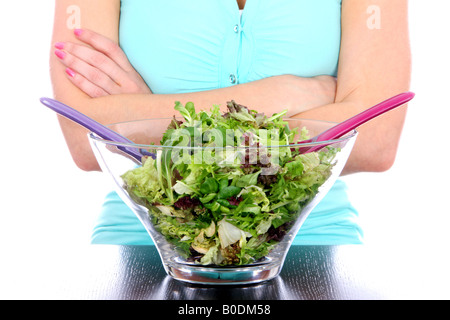 Jeune femme faisant jeter frais sain Salade verte dans un grand bol pour un repas végétarien sain isolé sur fond blanc Banque D'Images