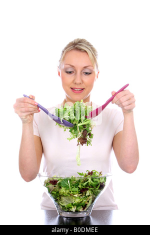 Jeune femme la préparation et le mélange d'un bol d'été frais feuilles de salade verte pour un repas sain isolé sur fond blanc Banque D'Images