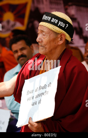 Un moine porte une plaque et porte un signe sur sa tête et est parmi les centaines de manifestants qui se sont réunis à Janpath, New Delhi Banque D'Images