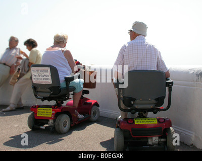 Couple de personnes âgées à la mer se déplacer sur les scooters motorisés sur prêt d'Shopmobility West Sussex Bognor Regis Banque D'Images