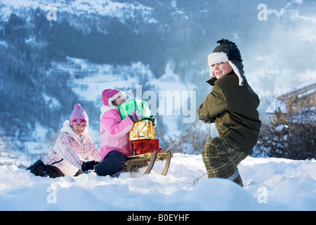 Des enfants jouent dans la neige avec présente Banque D'Images