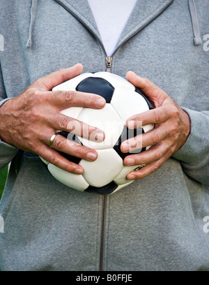 Mans hands holding football Banque D'Images