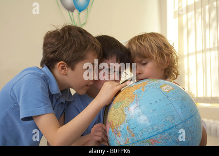 Les garçons à la terre à un globe Banque D'Images