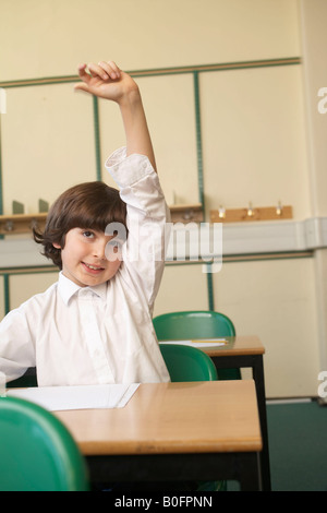 Garçon levant la main en classe Banque D'Images