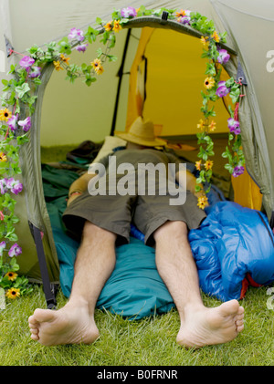 Man sleeping in tent avec chapeau sur le visage Banque D'Images