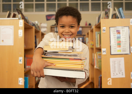 Boy carrying books, smiling Banque D'Images