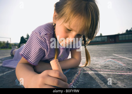 Jeune fille portant sur le dessin avec de la craie. Banque D'Images