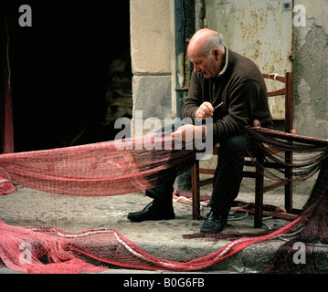 Vieux Pêcheur réparant ses filets Cefalu Sicile Italie L'UNION EUROPÉENNE. Banque D'Images