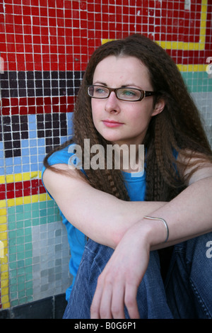 Une adolescente du Caucase à la colère assis sur le plancher d'un passage sous couvert de graffitis sur une propriété du conseil Banque D'Images