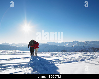 Couple en train de marcher dans la neige en montagne Banque D'Images