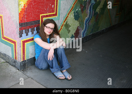 Les femmes de race blanche à la colère assis sur le plancher d'un passage sous couvert de graffitis sur une propriété du conseil Banque D'Images