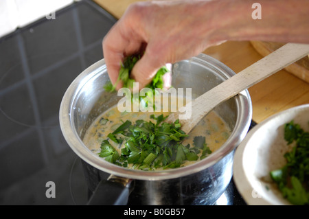 Ajouter le persil dans une soupe faite maison UK Banque D'Images