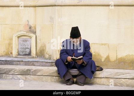 Un homme lit un livre à l'extérieur de la Grande Mosquée, Baku, Azerbaïdjan. Banque D'Images