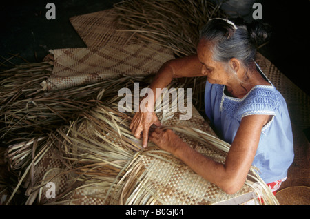 Une femme âgée le tissage de feuilles de palmier ensemble pour faire des nattes, Tarawa, Kiribati. Banque D'Images