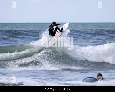 Porter une combinaison isothermique, surfer une vague. Cornwall, UK Banque D'Images