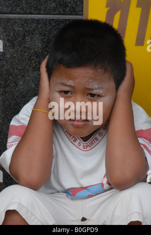 Boy est couvrant ses oreilles avec les mains d'explosions d'artifices , Phuket , Thaïlande Banque D'Images