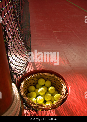 Les balles de tennis dans un panier sur le sol rouge de la tennis à Hampton Court Palace, Angleterre Banque D'Images