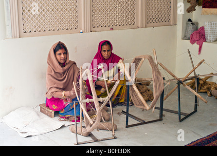 Inde JAIPUR Deux femmes indiennes en saris colorés avec bindi sur leurs fronts pelote fil de laine qui sera utilisé pour faire des tapis Banque D'Images