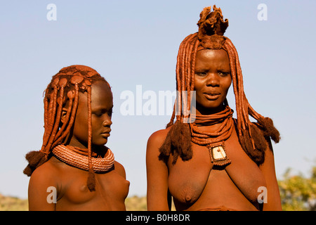 Femme Himba jeunes et célibataires sur la gauche debout à côté d'une femme Himba mariés à droite, Kaokoveld, Namibie, Afrique Banque D'Images