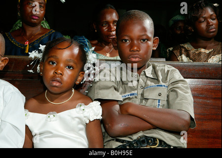 Garçon et fille assise sur un banc d'église, Douala, Cameroun, Afrique Banque D'Images