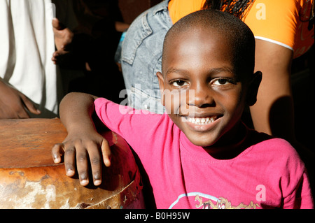 Smiling boy leaning on un tambour africain traditionnel à un mariage à Douala, Cameroun, Afrique Banque D'Images