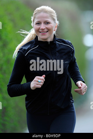 Les jeunes, smiling blonde woman jogging survêtement noir Banque D'Images