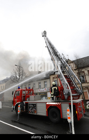 Les pompiers de combattre un feu de toit à l'aide de flexibles à haute pression et une échelle mobile à Bergisch Gladbach, en Rhénanie du Nord-Westphalie, G Banque D'Images