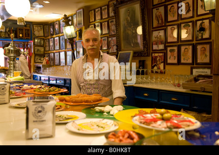 Barman, barman derrière âgées servis au bar à tapas Marpy, murs couverts de souvenirs de tauromachie, Saragosse, Saragosse, Ara Banque D'Images