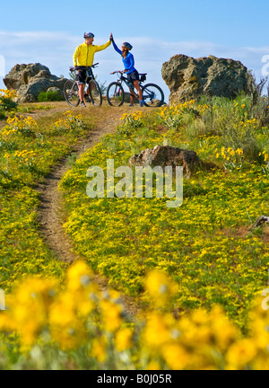 Près de Boise IDAHO un couple high fives et des vélos de montagne parmi les fleurs sauvages dans les contreforts d'une belle journée de printemps Banque D'Images
