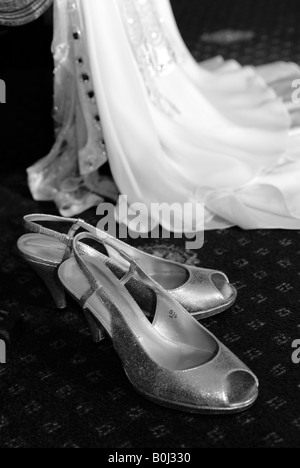 Une robe de mariée dans la chambre d'hôtel avant son mariage. Ses chaussures sont à l'avant-plan Banque D'Images