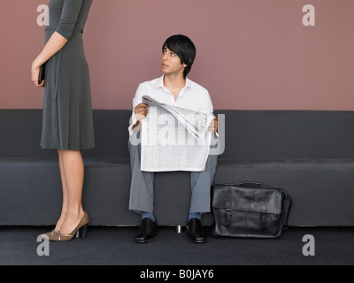 Young Businessman Reading Newspaper in Lobby Banque D'Images