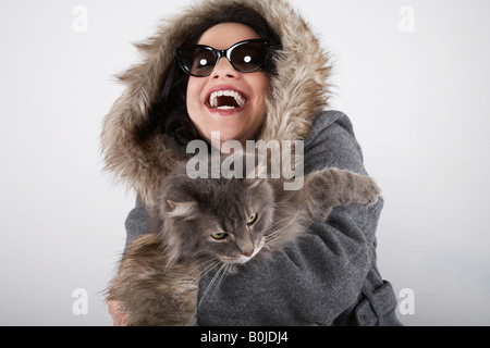 Femme portant manteau à capuchon, holding cat, rire Banque D'Images