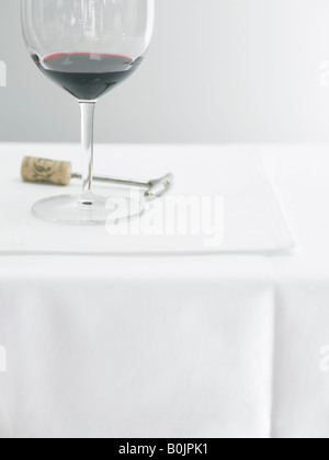 Verre de vin rouge sur la table avec tire-bouchon Banque D'Images