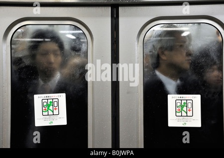 Avis de voyageurs entassés dans les transport via windows sur train occupé durant les heures de pointe à Tokyo au Japon Banque D'Images