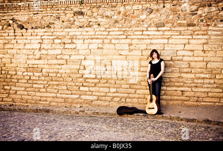 Artiste de rue, debout avec sa guitare sur le mur Banque D'Images