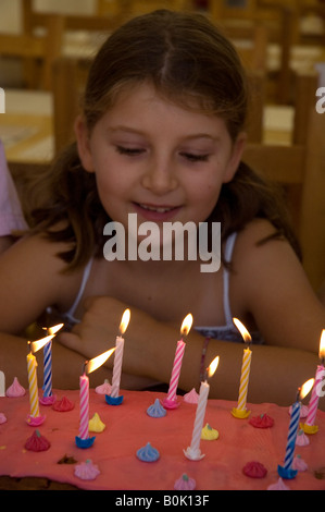 Neuf ans girl blowing out candles on cake. Banque D'Images