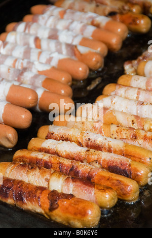 Enveloppé de bacon hot-dogs sur le grill sizzle Banque D'Images
