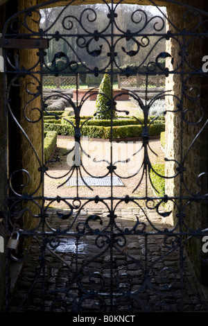 Voir par une porte pour le jardin clos adjacent à la Ruines Cowdray, Midhurst, West Sussex, Angleterre. Banque D'Images