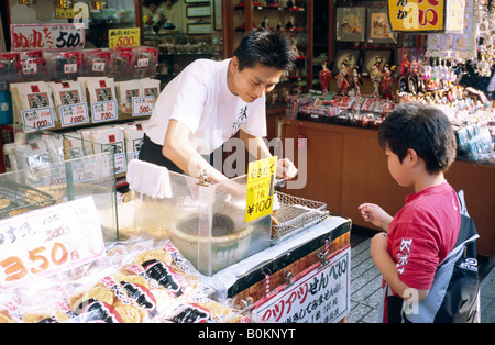 Garçon achète des bonbons sur centre commercial Nakamise Dori dans le quartier historique d'Asakusa de Tokyo. Banque D'Images