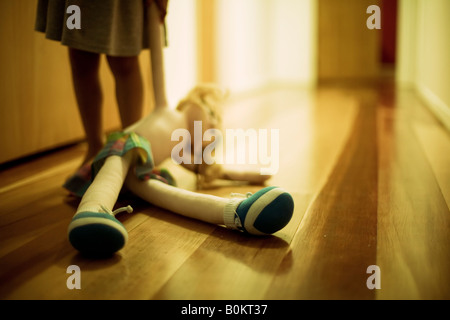 Jeune fille âgée de quatre porte toy doll dans hall Banque D'Images