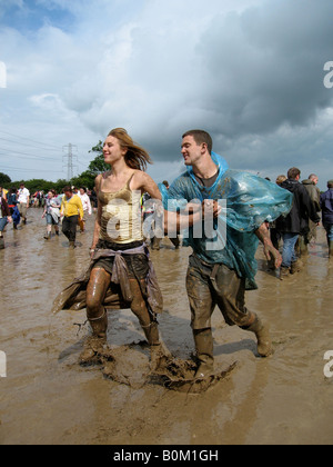 Fêtards s'exécuter dans la boue à Glastonbury Festival 2007 Banque D'Images