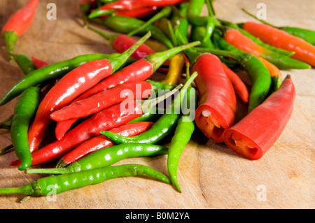 Une sélection de piments rouges et verts colorés sur une planche à découper. Banque D'Images