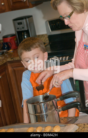 L'activité de famille d'accueil qui fait le beurre d'arachide de chocolat oeufs de Pâques traditionnel traiter. Petit-enfant grand-mère Banque D'Images