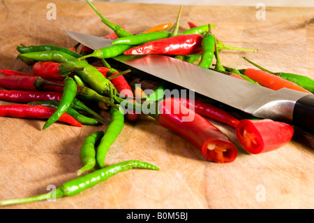 Une sélection de piments rouges et verts colorés avec un couteau sur une planche à découper. Banque D'Images