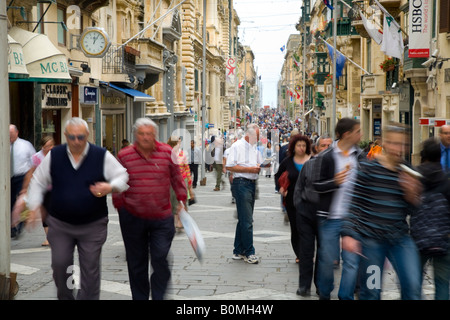 Principale rue commerçante avec des foules de touristes à shoppers et la principale rue commerçante de la rue principale et sur la maison de vacances île de La Valette, Malte. Banque D'Images