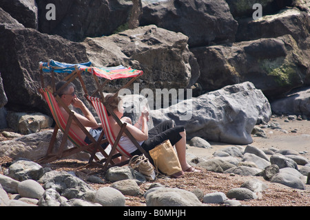 Couple d'âge mûr prenant un bain de soleil sur la plage à Steephill Cove, île de Wight, Angleterre, Royaume-Uni Banque D'Images