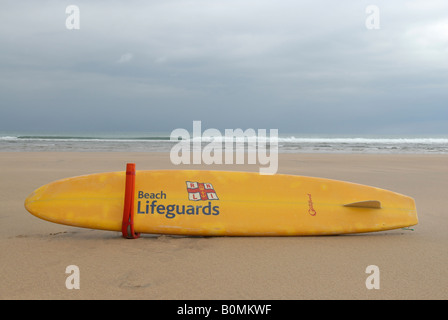 Un sauveteur RNLI paddle board sur la plage à Bude en Cornouailles du Nord, en Angleterre, UK. Banque D'Images