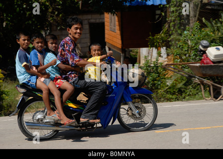 Famille le scooter dans village de pêcheurs, Côte d'Andaman, Thaïlande Banque D'Images